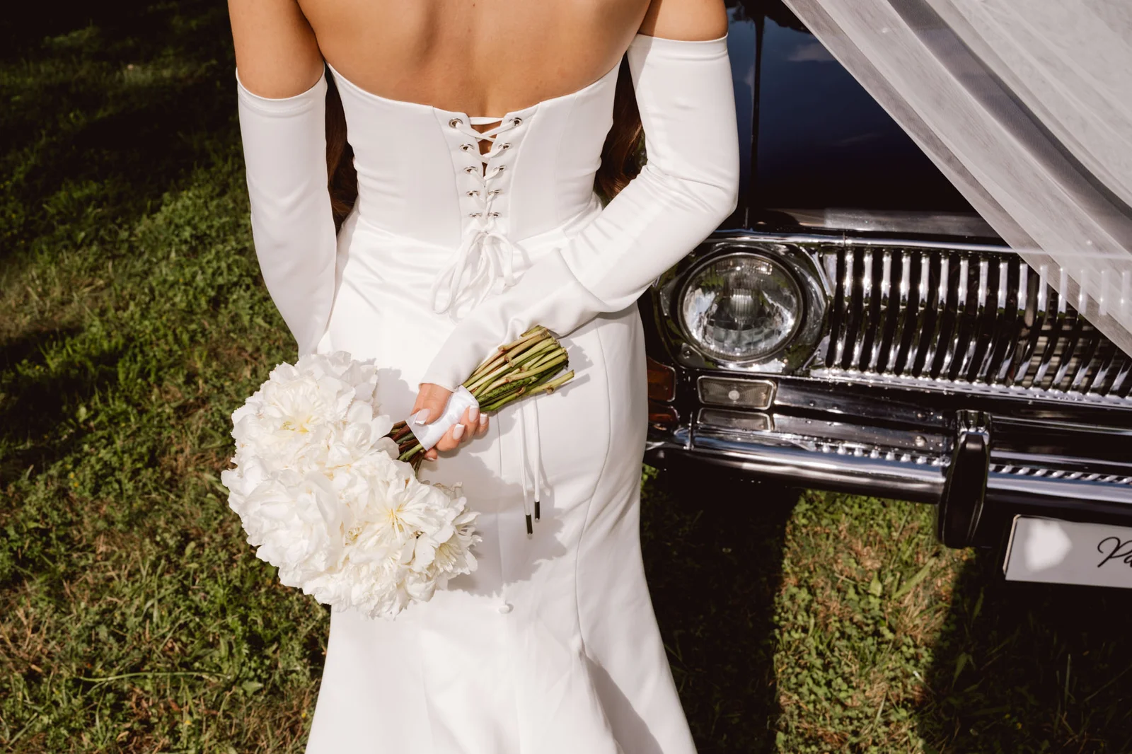 Panna młoda z bukietem za plecami