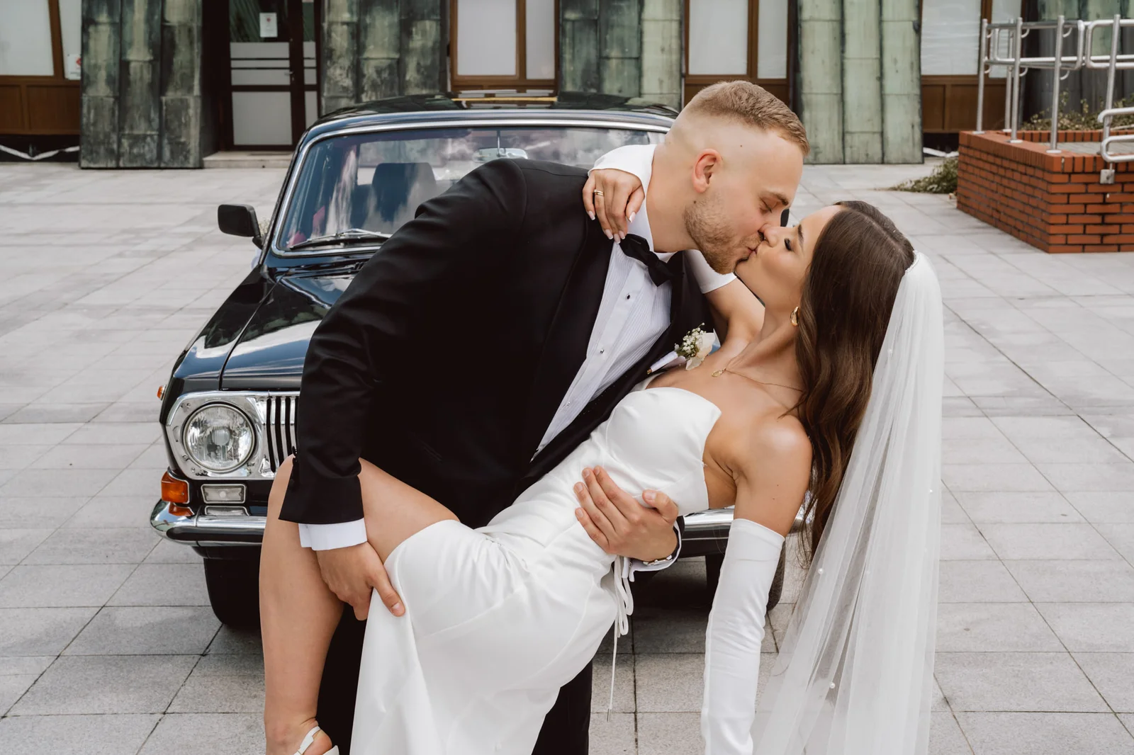 Pocałunek pary młodej przy samochodzie